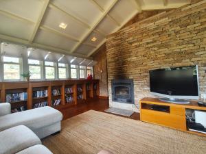 a living room with a tv and a brick wall at Quinta de Gonçalo in Guarda