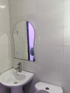 Un baño con lavabo, espejo e inodoro. en Graciano Suit's, en Lagos 2 fotos más