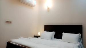 une chambre avec un lit avec des draps blancs et des oreillers dans l'établissement Luxury 1BHK in Gulberg Arena with Balcony, à Islamabad