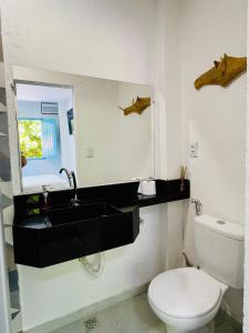 a bathroom with a sink and a toilet and a mirror at CASINHA JASMIM, vila florescer, centro histórico!! in Piranhas +21 photos