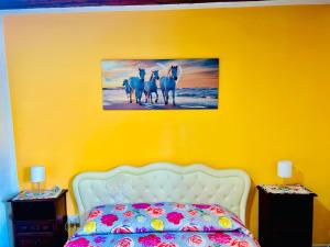 a yellow bedroom with a bed and a picture of four horses at Civico 31 in Terralba +17 photos