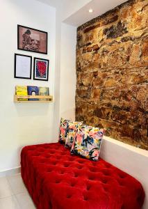 a red couch in a room with a brick wall at CASINHA JASMIM, vila florescer, centro histórico!! in Piranhas