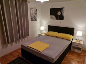 ein Schlafzimmer mit einem Bett mit gelber Bettwäsche und zwei Lampen in der Unterkunft Apartment Sanja in Rab