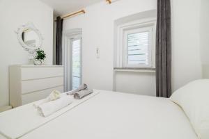 a white bedroom with a bed and a mirror at Apartment Lozann in Povile