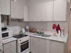 a kitchen with white cabinets and a stove and a sink at Ef-xaris in Perea