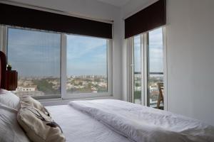 a white bedroom with large windows and a bed at Penta Square Modern & Luxury Apartments City View DHA Lahore in Lahore