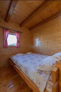 a bed in a log cabin with a window at Vajat Bella in Zlatibor