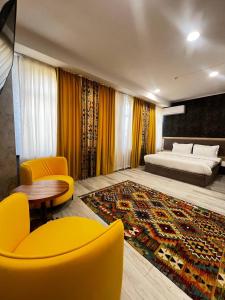 a bedroom with a bed and a table and yellow chairs at Badyan Boutique Hotel in Bukhara in Bukhara