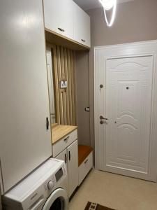 a laundry room with a white door and a washing machine at Saranda Apartment in Polisi i Vogël