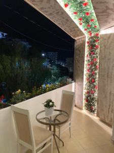 a table and chairs on a balcony with flowers at Saranda Apartment in Polisi i Vogël