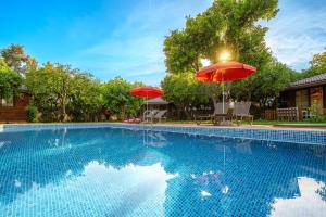 a swimming pool with two umbrellas next to a house at Mandarin Bungalow in Alanya +8 photos