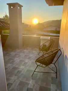 two chairs on a balcony with the sunset in the background at Kitnet Espaço Aconchego in Alfredo Wagner +2 photos