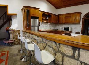 a kitchen with wooden cabinets and white stools at The chill spot in Tagarades