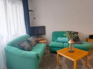 a living room with two green chairs and a table at Pfeiren Leukerbad in Leukerbad