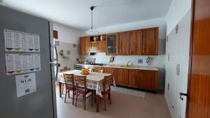 a kitchen with wooden cabinets and a table with chairs at La Casa Sicula in Capri Leone