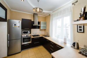a kitchen with black cabinets and a stainless steel refrigerator at Cottage Prestige in City Centre & dom4 in Grodno