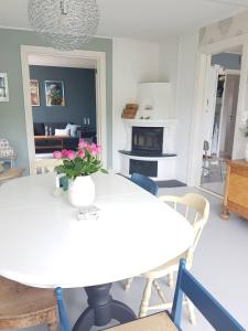 a dining room with a white table with flowers on it at Solheimhuset - feriehus nær Tjøme og VerdensEnde in Tokenes
