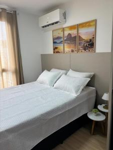 a bedroom with a bed with three paintings on the wall at Loft Boa Viagem - Uni Studios in Niterói