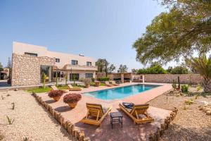 a swimming pool with chairs and a house at Villa Talya in Ghazoua