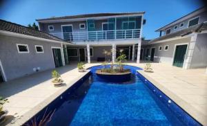 a swimming pool in front of a house at Suite Dunas do Peró in Cabo Frio