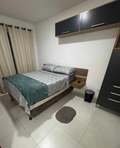 a bedroom with a bed and a cabinet and a rug at Suite Dunas do Peró in Cabo Frio