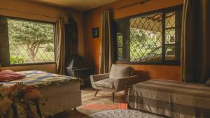 a bedroom with a bed and a chair and windows at Sitio em Teresópolis com Piscina e Churrasqueira in Teresópolis
