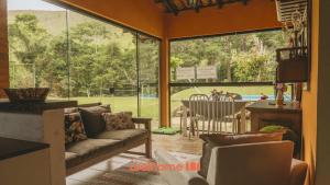 a living room with a couch and a large window at Sitio em Teresópolis com Piscina e Churrasqueira in Teresópolis