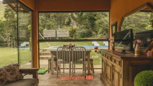 a living room with a table and chairs and a television at Sitio em Teresópolis com Piscina e Churrasqueira in Teresópolis +24 photos