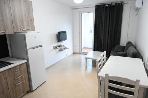 a kitchen and living room with a white refrigerator and a table at Vacation Apartments - Shengjin in Shëngjin +4 photos