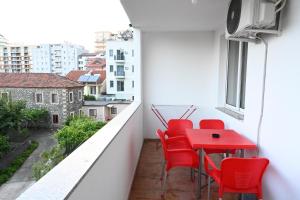 a balcony with red chairs and a red table at Vacation Apartments - Shengjin in Shëngjin