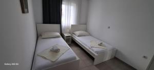two beds in a room with white walls at Apartmani BRNADA in Trogir