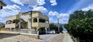 a yellow building with a car parked in front of it at Apartmani BRNADA in Trogir