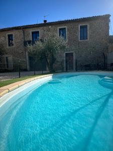 a large blue swimming pool in front of a building at Au cocon des Corbière - La bohème in Lézignan-Corbières