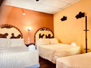 a hotel room with two beds with white sheets at Hotel Chilero Y Café in Antigua Guatemala