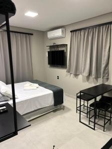 a bedroom with a bed and a table and a television at APARTAMENTOS BORA BORA II vila nova 600 METROS DA EXPOVILLE in Joinville