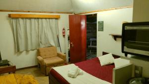 a bedroom with a bed and a chair and a television at Antucalhue Mountain Resort in Antuco