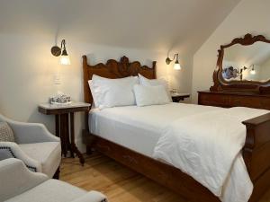 a bedroom with a bed with a mirror and a chair at The Red House Fredericton in Fredericton