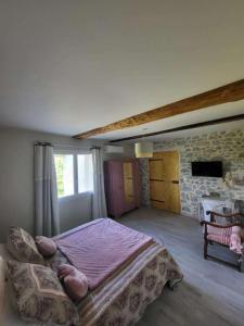 ein Schlafzimmer mit einem großen Bett und einer Steinwand in der Unterkunft Domaine de LOLI in Saint-Girons