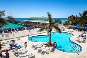 a pool with a palm tree and chairs and the ocean at Luxurious 2BD Condo with Direct Ocean Front & Resort Pool in Sunny Isles in Sunny Isles