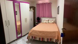 a small bedroom with a bed and pink curtains at Casa Bella Temporada in Campina Grande