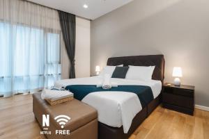 a bedroom with a large bed and a ottoman at Designer Luxury 3BR Retreat near Pavilion & KLCC in Kuala Lumpur