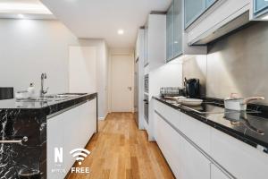 a kitchen with white cabinets and a wooden floor at Designer Luxury 3BR Retreat near Pavilion & KLCC in Kuala Lumpur