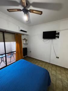 Un dormitorio con una cama azul y un televisor de pantalla plana. en Apartamento Pacifico, en Bahía Blanca