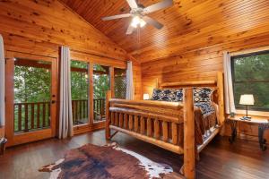 a log cabin bedroom with a bed and a ceiling fan at Black Bear Cove in Gatlinburg