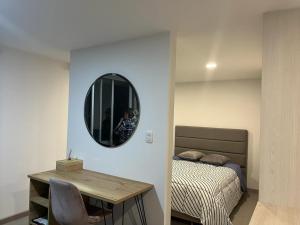 a bedroom with a bed and a table and a mirror at PAIPA Hermoso apartamento en RUSTICO 709 in Paipa