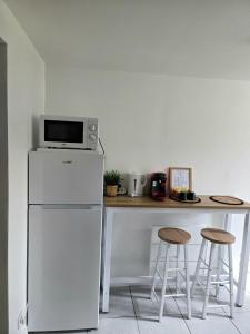 a kitchen with a counter with a refrigerator and stools at Grand studio cosy proche Paris in Épinay-sur-Seine +15 photos