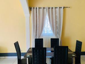 a dining room table and chairs in front of a window at ELG Appart in Kribi