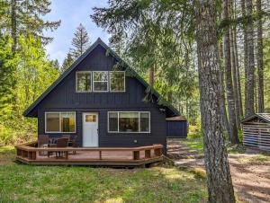 a black tiny house in the woods with a deck at Powder to the People in Packwood