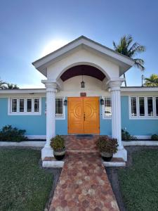 een blauw huis met een gele deur en pilaren bij Blue Orchid Palms in Nassau