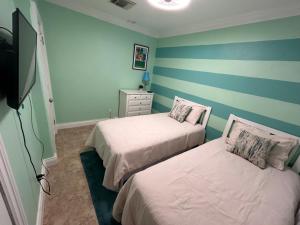 twee bedden in een kamer met blauwe en groene strepen bij Blue Orchid Palms in Nassau